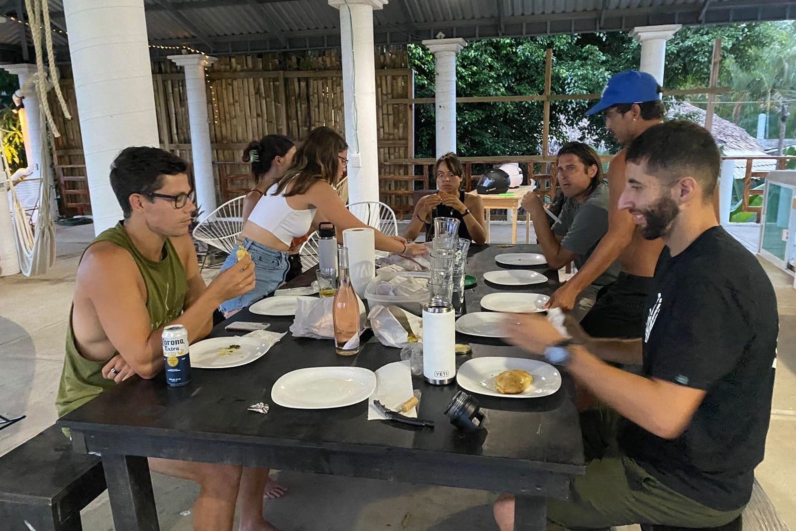 Flow Coliving guests sharing a group dinner at the long communal table on the open-air terrace