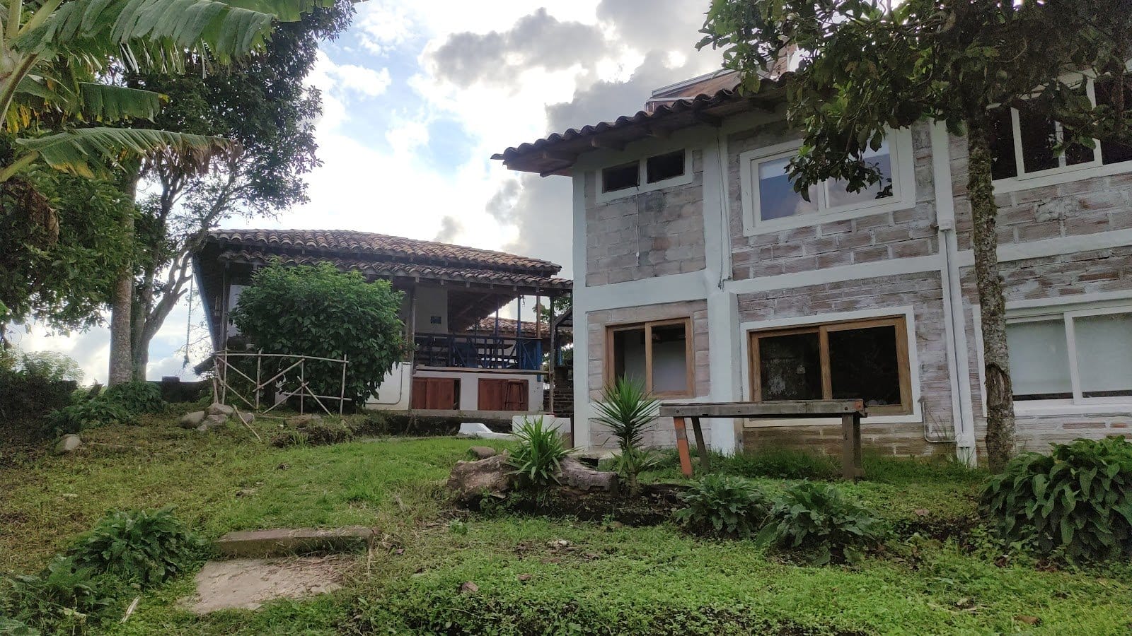 Riverside ecoliving whitewashed stone-and-timber guesthouse building amid green Andean hills