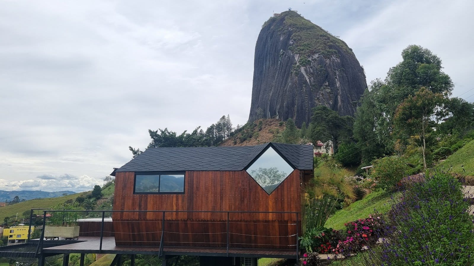 A-frame wooden cabin perched on the hillside below El Peñol at Riverside ecoliving Guatapé