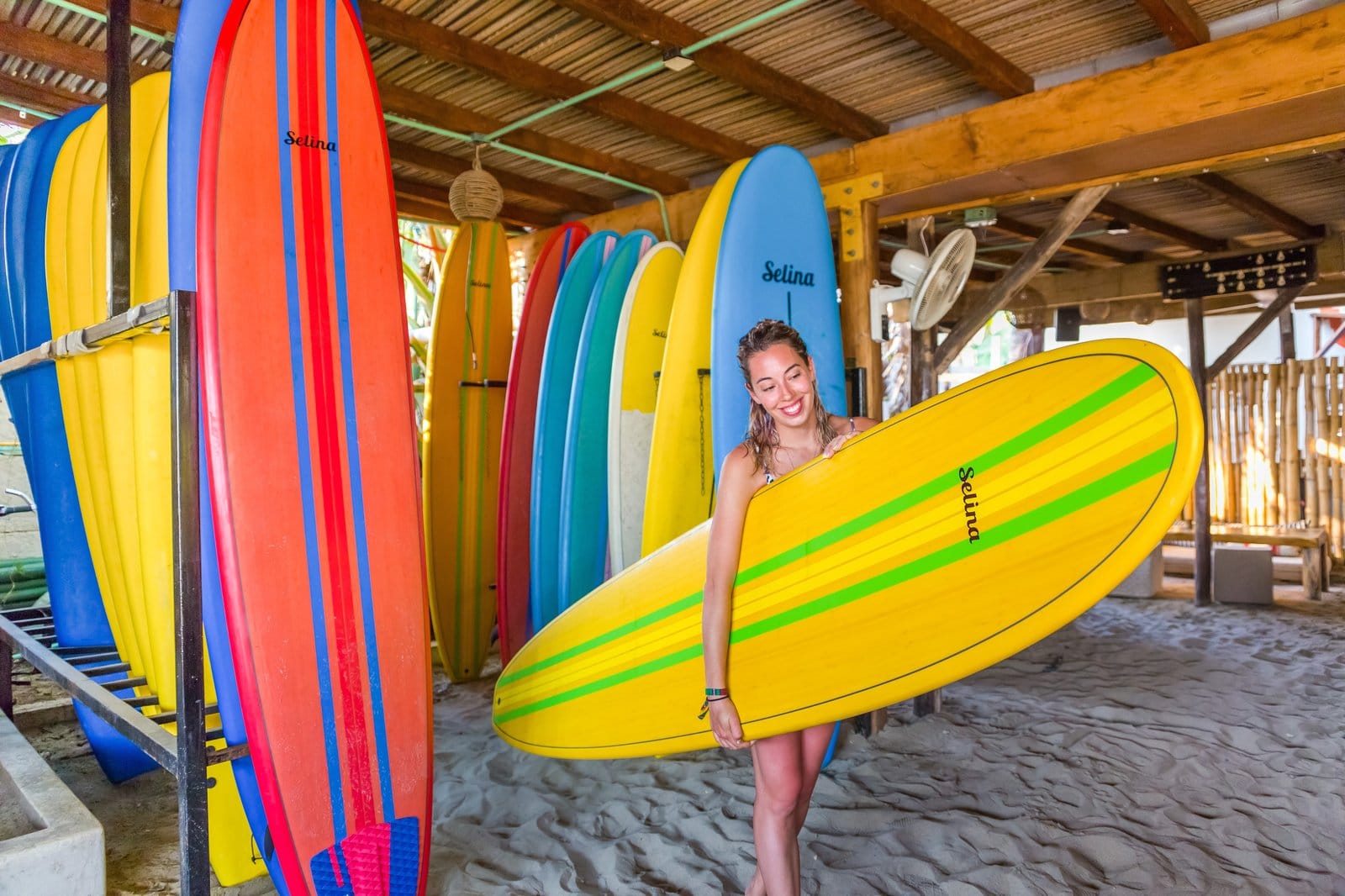 Guest smiling with a Selina surfboard at the surf rental area at Selina Puerto Escondido