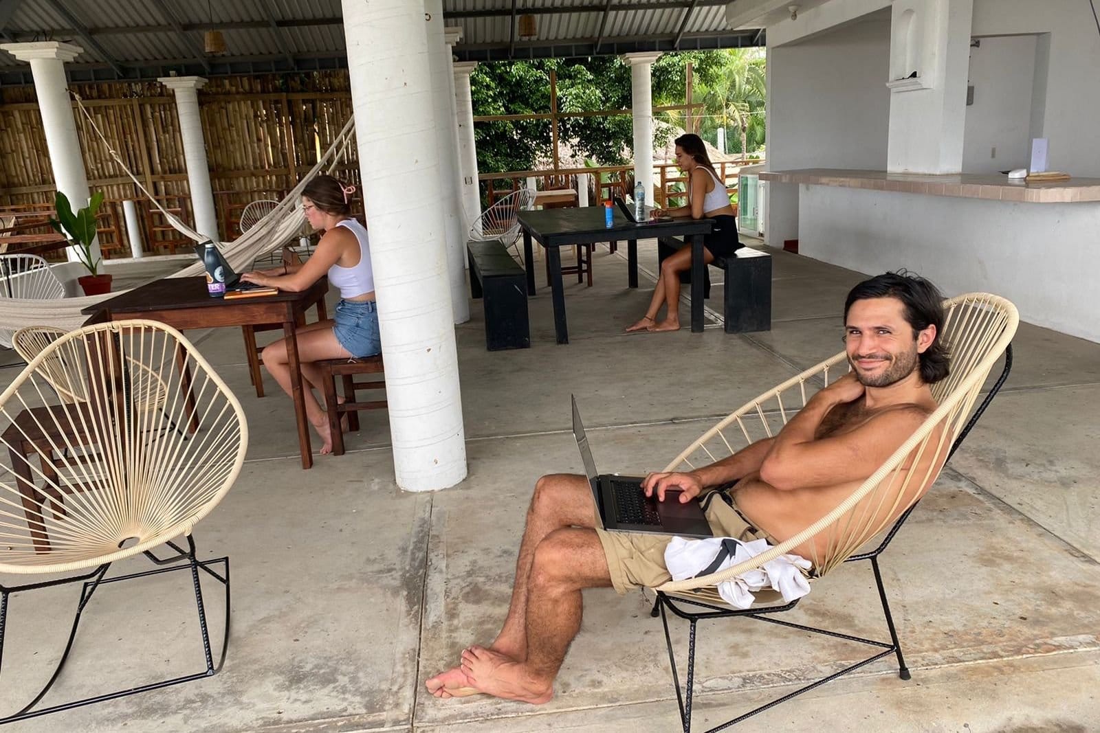 Flow Coliving residents working on laptops in the open-air common area terrace