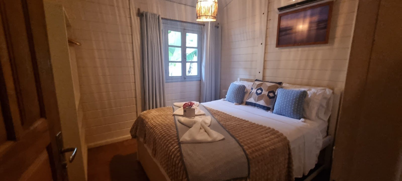 Bright bungalow bedroom with neatly made bed and framed art at FlowHouse Jeri