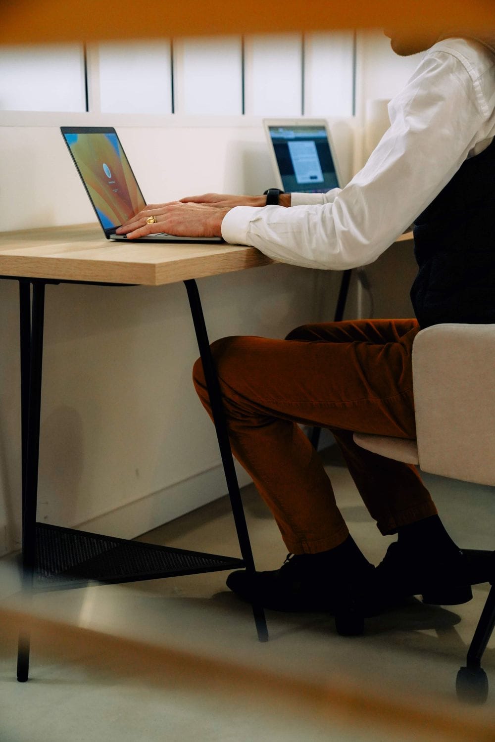 Resident working on a laptop at a compact desk in the Outsite Bordeaux lounge workspace