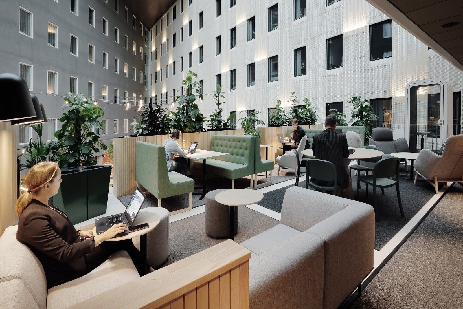 Coworking lounge with sofas, plants and people working on laptops at VALO Hotel & Work