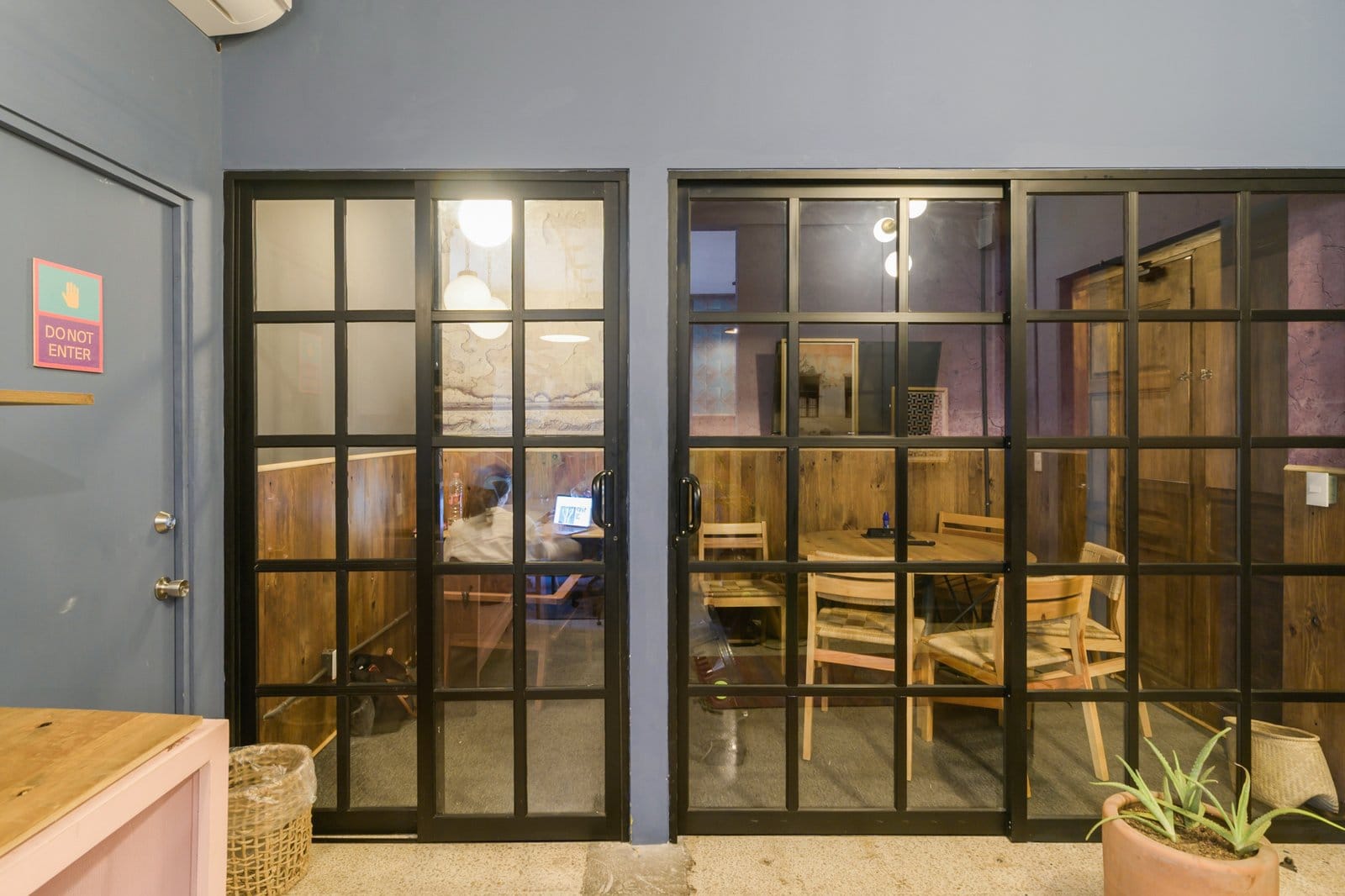 Person working at a laptop inside the glass-walled coworking room at Selina Oaxaca