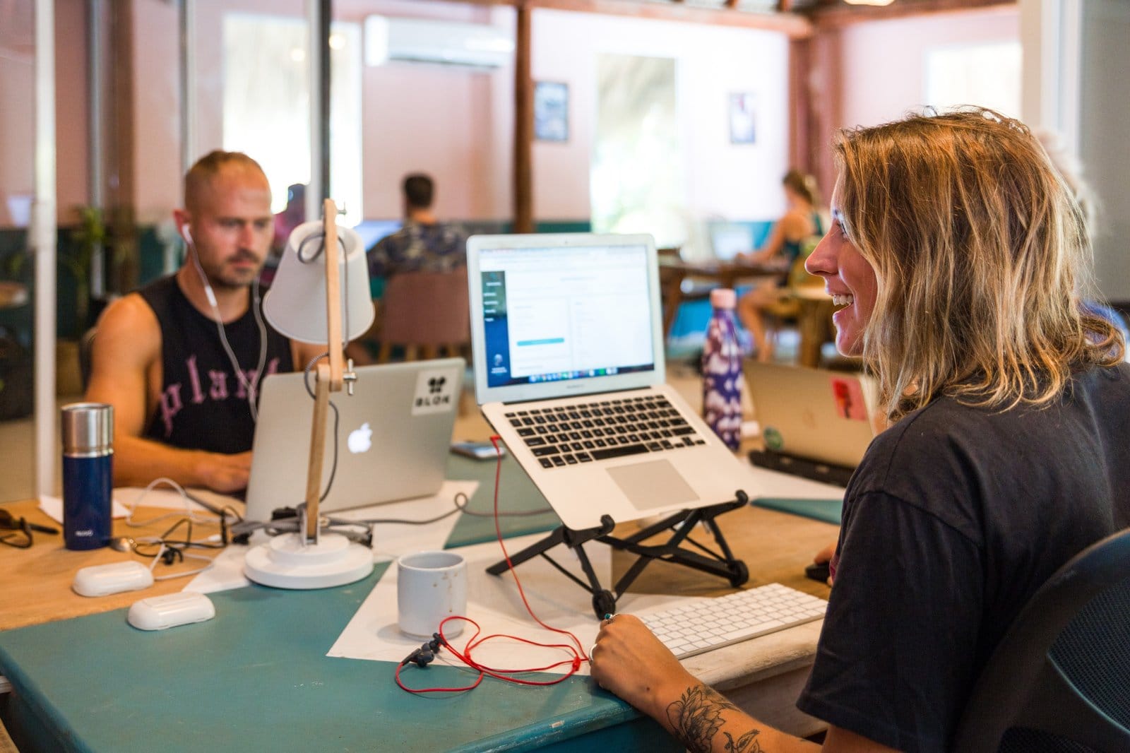 Two digital nomads working on laptops with stands and desk lamps at the Selina Puerto Escondido coworking space
