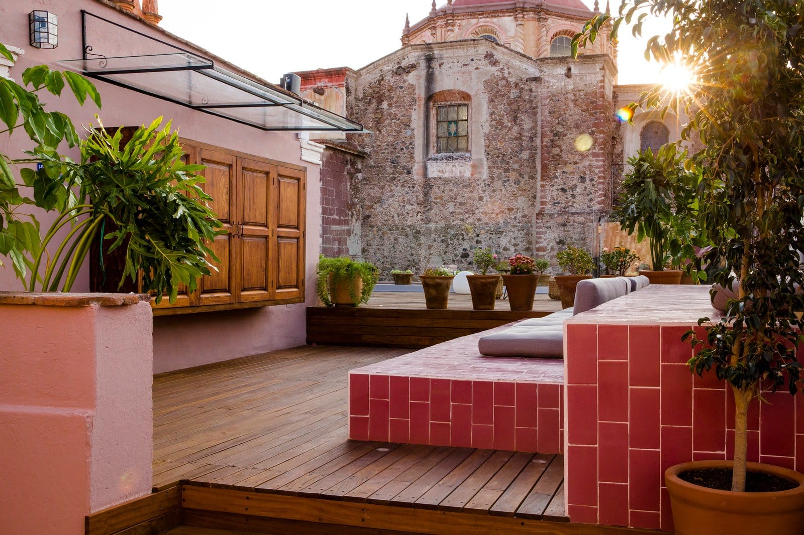 Private rooftop terrace at Selina San Miguel de Allende with wood deck, lounge seating, and the historic cathedral glowing in golden evening light