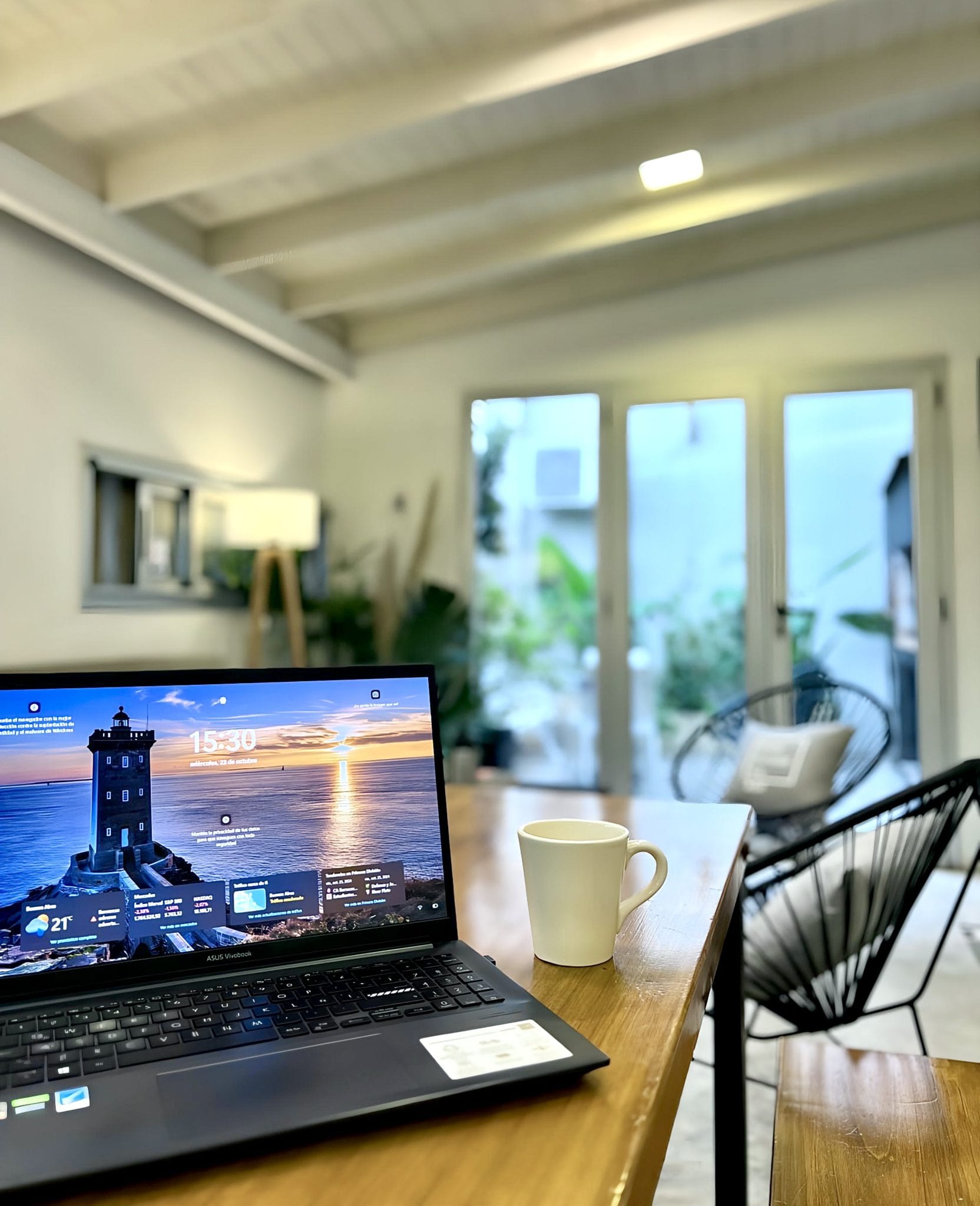 Spacious shared workspace with laptop and garden-facing windows at Vibrant Coliving Buenos Aires