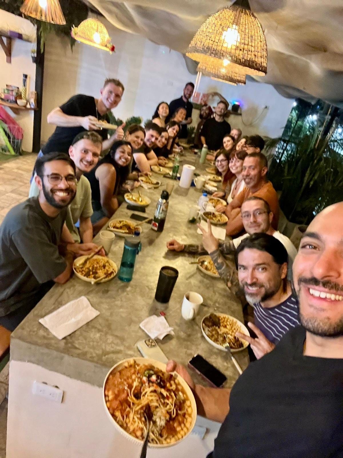 Group of nomads sharing a lively communal dinner at Co404 Medellin