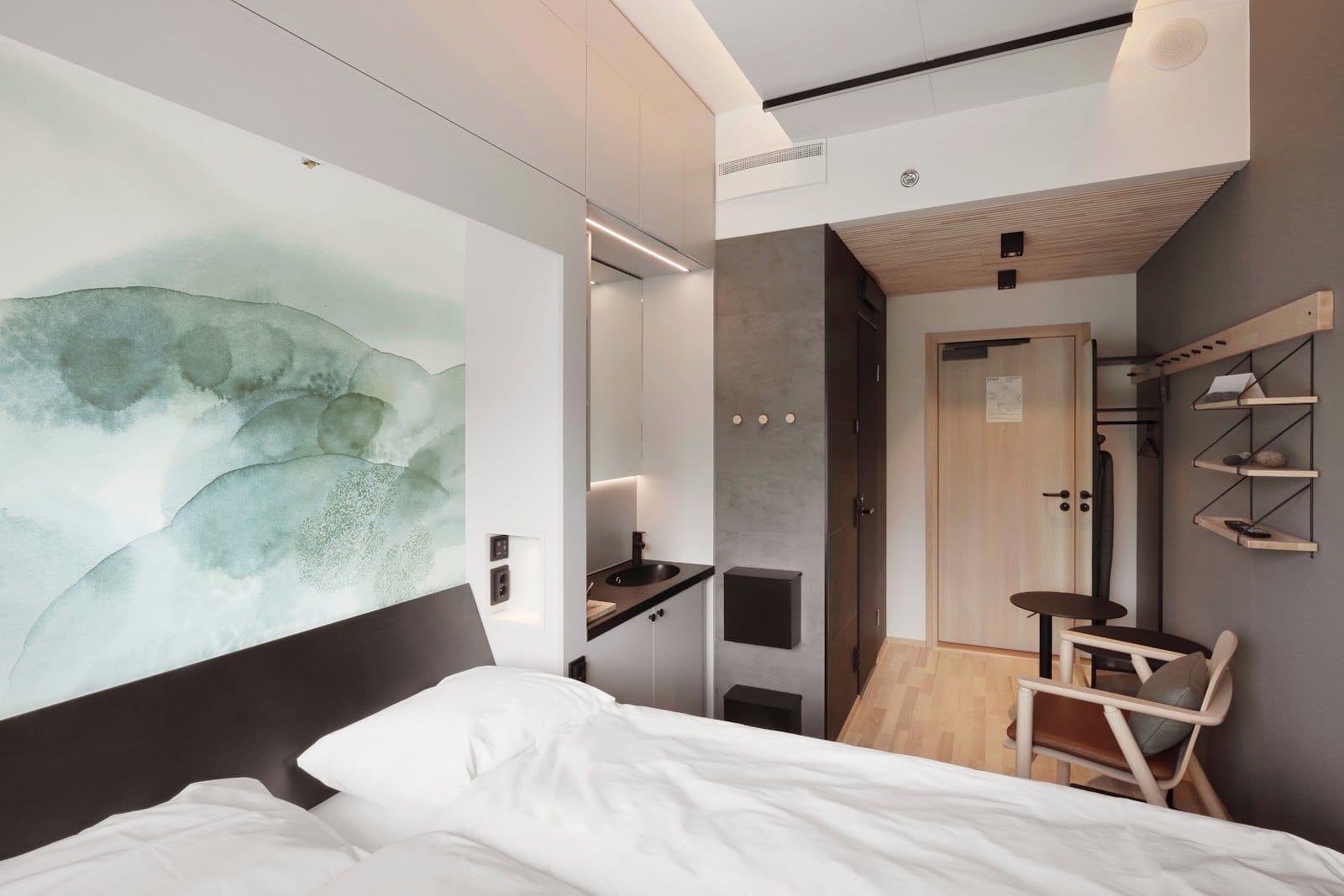Stylish modern bedroom with large watercolor mural at VALO Hotel & Work