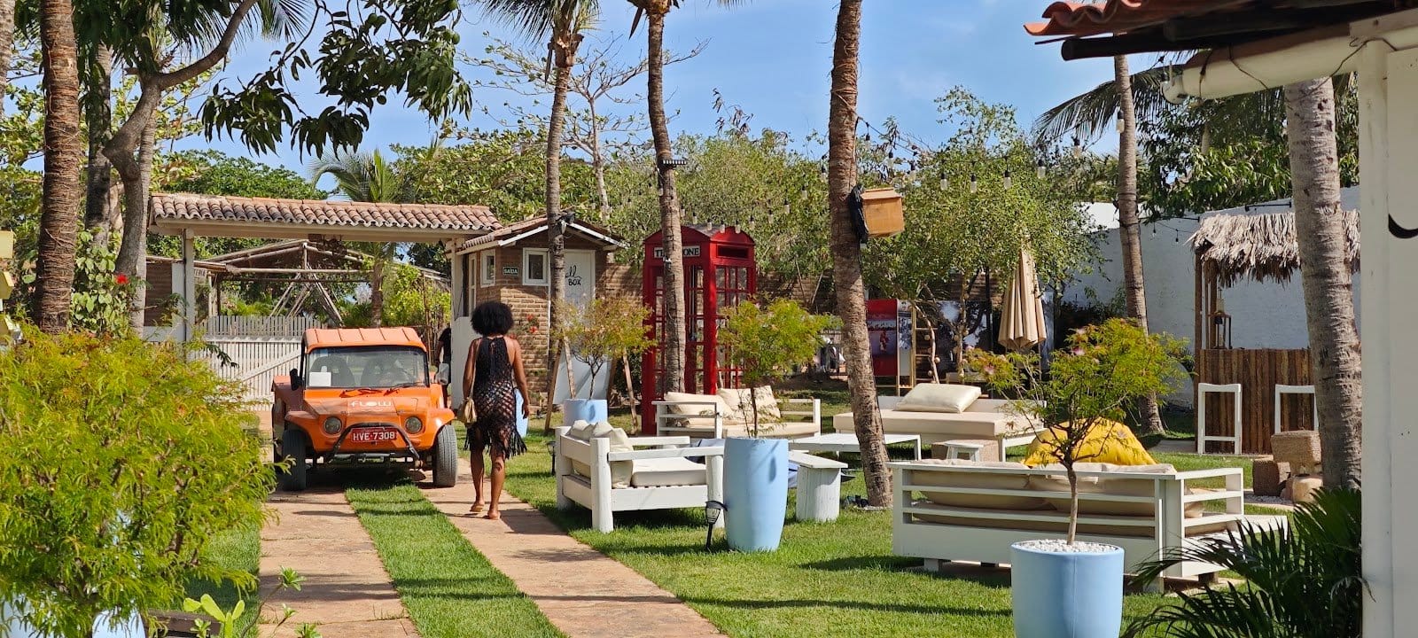 Guest walking through the garden lounge area with white sofas and palm trees at FlowHouse Jeri