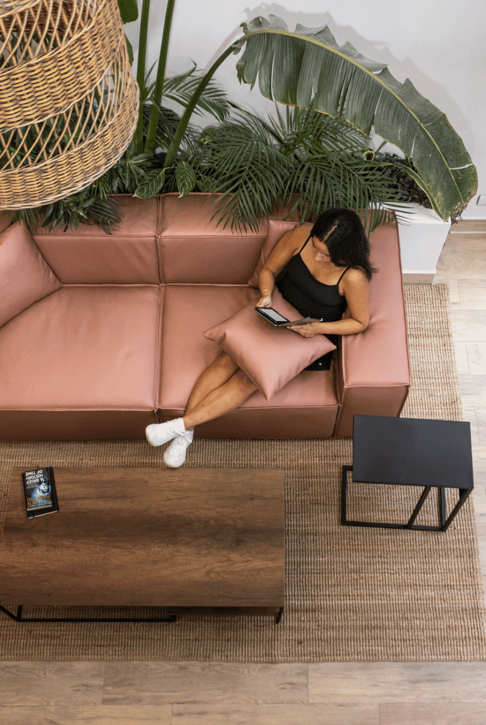 Guest relaxing on a leather sofa among tropical plants in the Outsite Medellín lounge