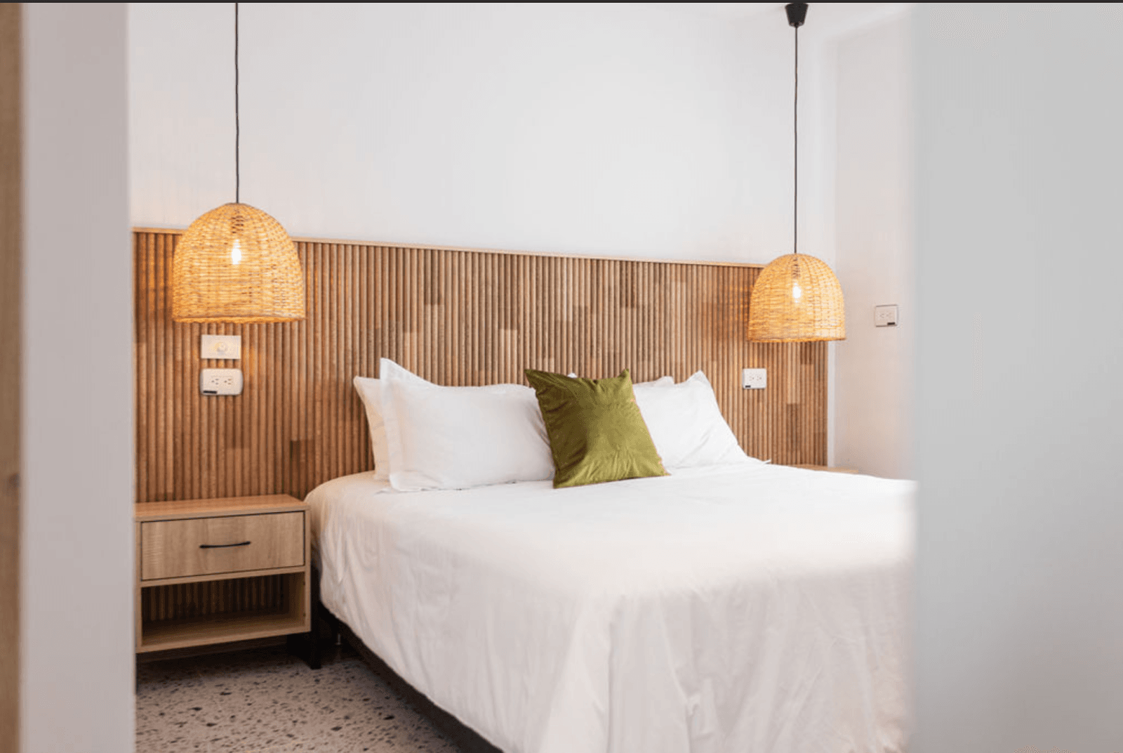 Stylish private bedroom with wood-slat headboard and wicker pendant lamps at Outsite Medellín