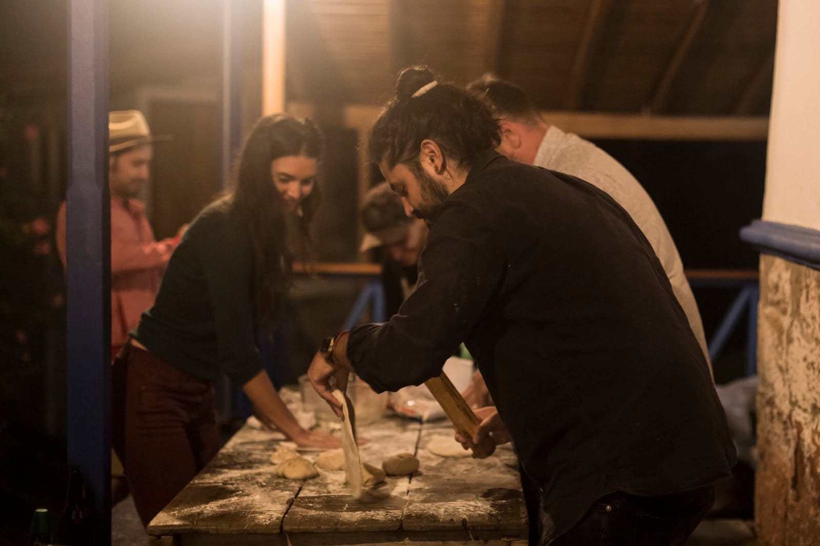 Guests at Riverside ecoliving gathering around a long wooden table to make pizza dough together