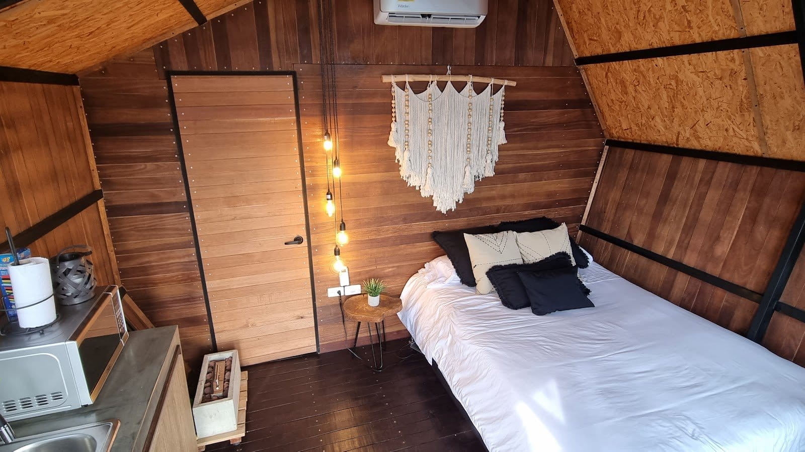 Cozy wooden cabin interior with bed and warm lighting at Riverside ecoliving Guatapé
