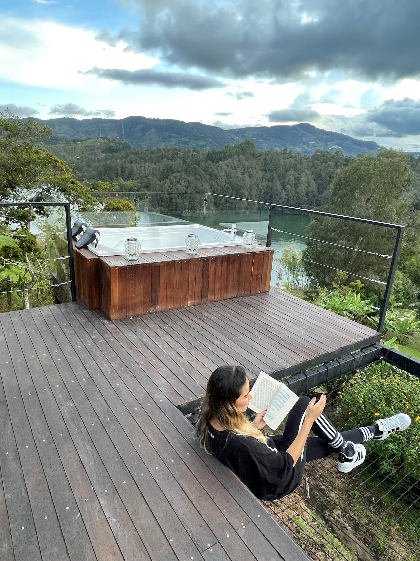 Guest relaxing and reading on the deck beside the jacuzzi at Riverside ecoliving Guatapé