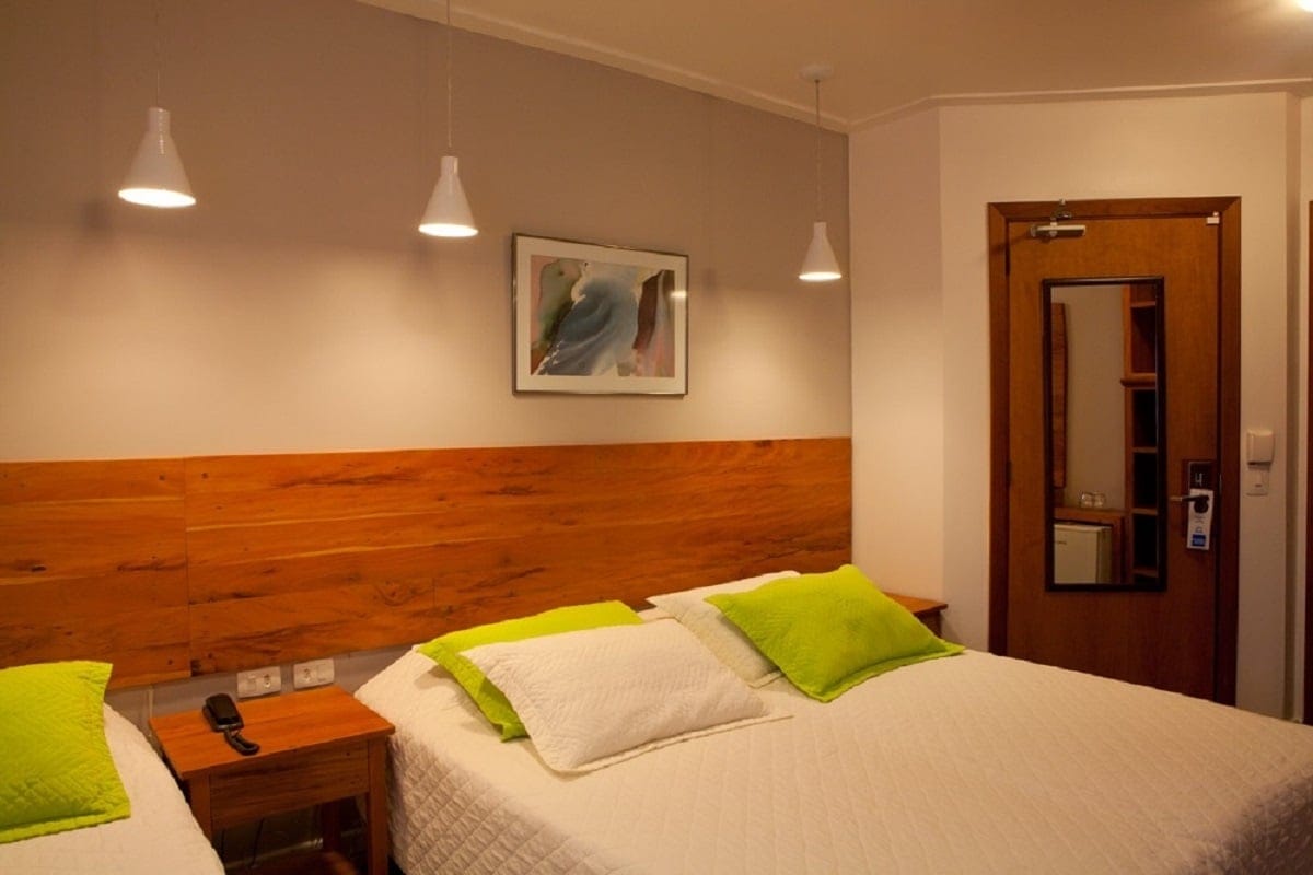 Bright guest room at Pousada Villa Capivary with a reclaimed-wood headboard, twin beds and lime-green accents