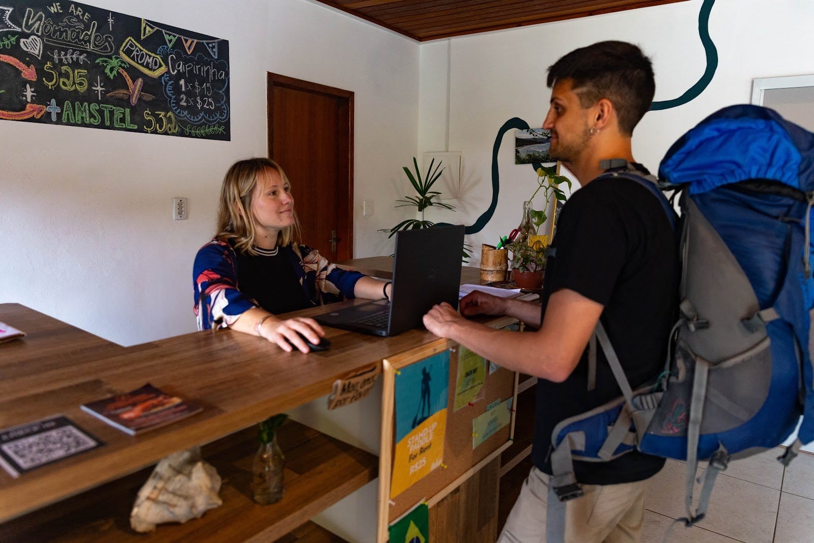 Guest checking in at the travel-themed reception of Nômades Riverside hostel in Florianópolis