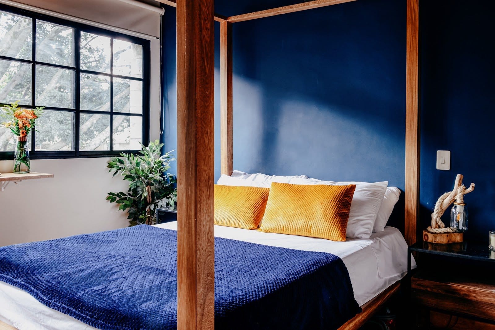 Private bedroom with a wooden four-poster bed and deep blue walls at Balu Coliving Medellin