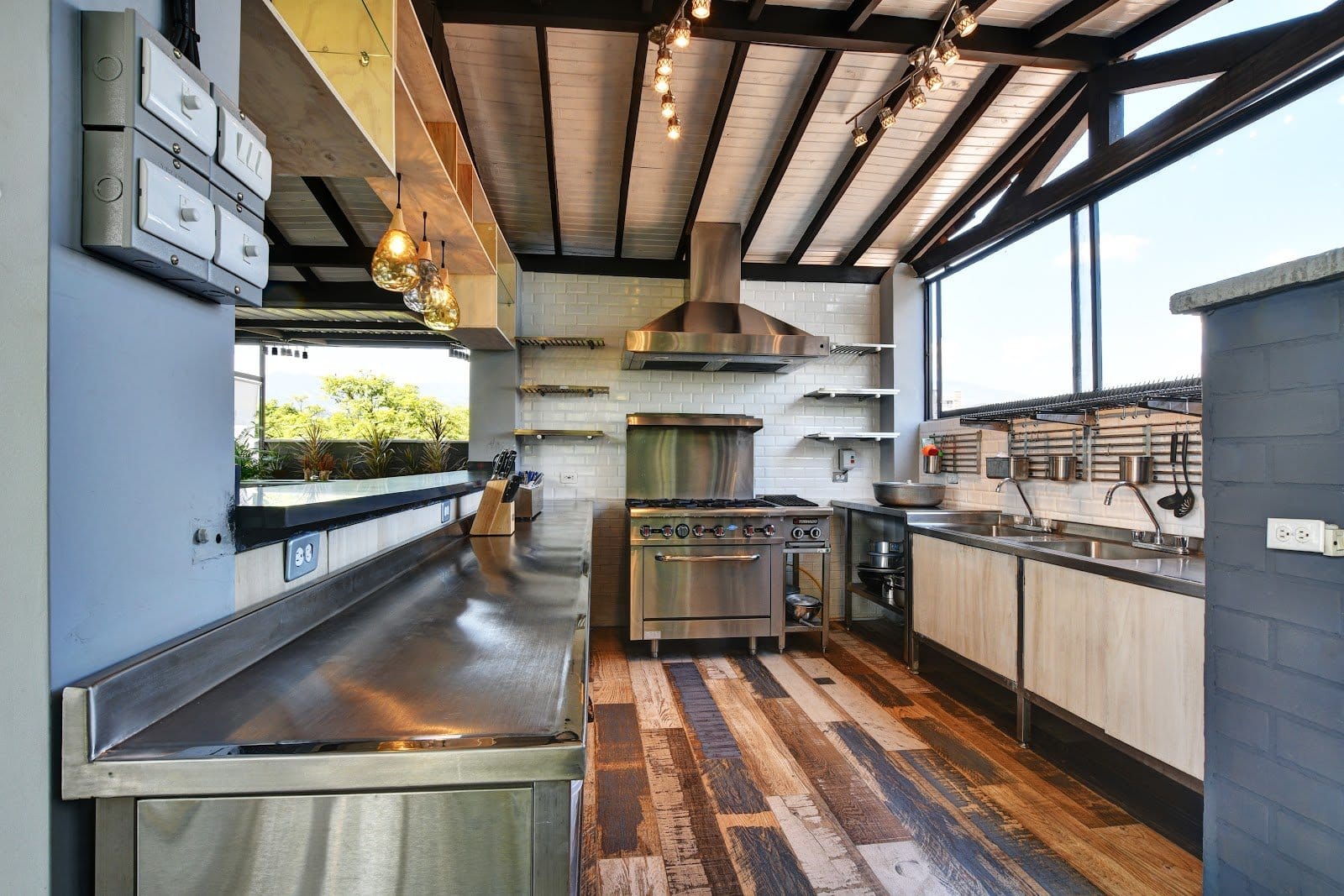 International House Co-Living open chef's kitchen with stainless steel range, exposed wood-beam ceiling and mountain-view windows
