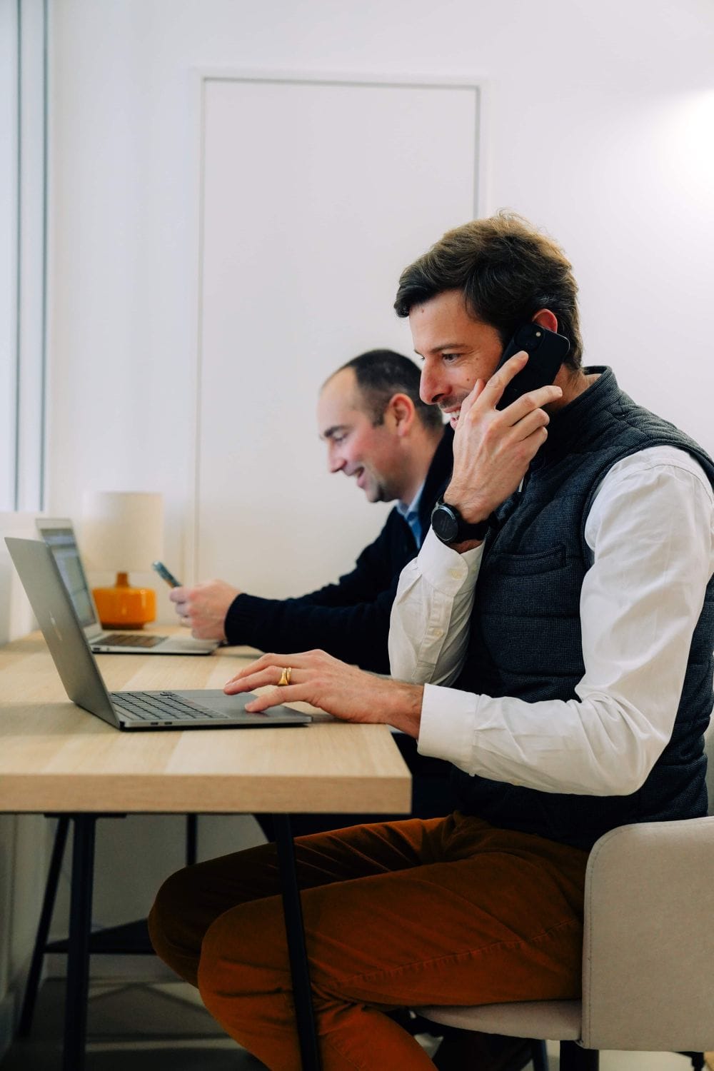Two residents working at laptops in the shared workspace at Outsite Bordeaux
