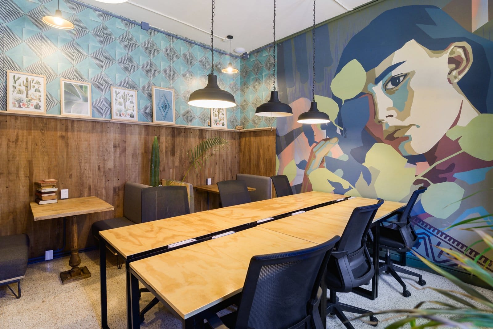 Dedicated coworking and meeting room at Selina Oaxaca with long wooden table, ergonomic chairs and colorful mural