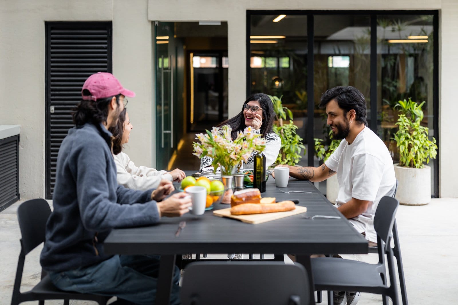 Four residents sharing a candid outdoor meal in the courtyard at Outsite Mexico City Roma Sur