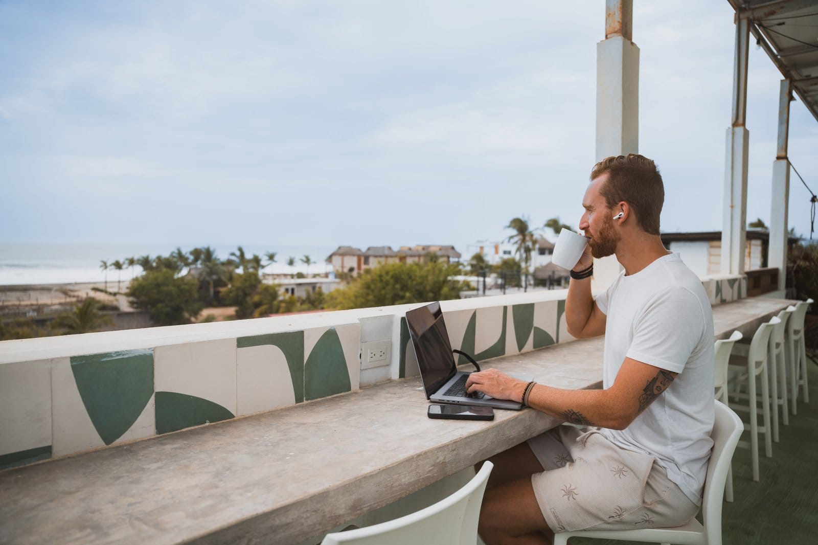 Resident working on a laptop at the rooftop workspace at Surfbreak PXM overlooking the Pacific Ocean
