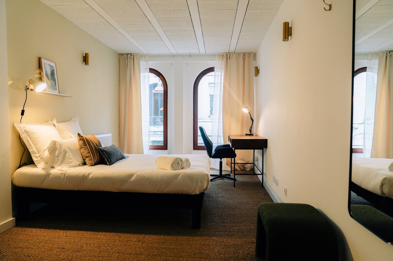 Private ensuite room at Outsite Bordeaux with double bed, desk, arched window, and soft green walls