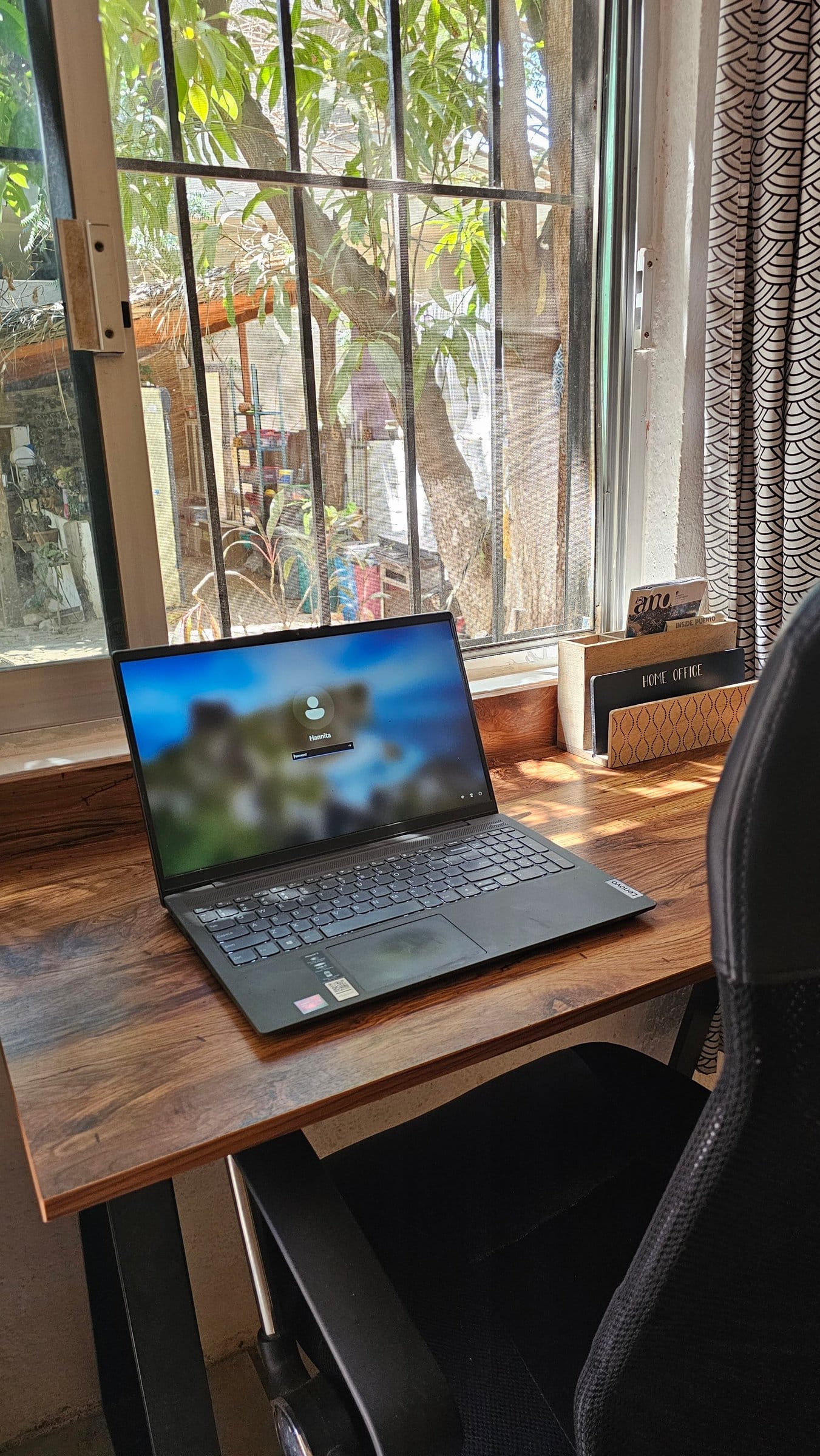 Dedicated desk setup at El Mundito Coliving — laptop open at window-side workstation with ergonomic chair