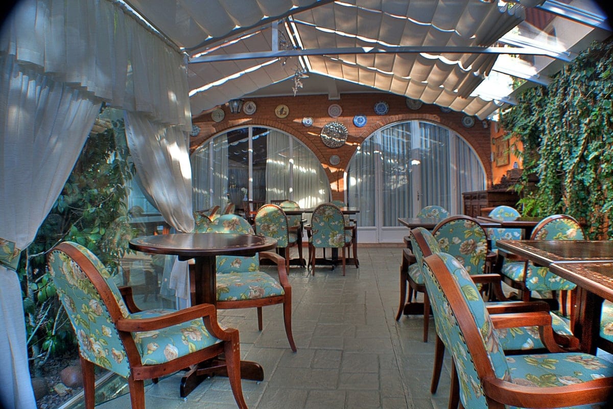 Glass-roofed veranda lounge at Pousada Villa Capivary with floral-upholstered armchairs and garden views