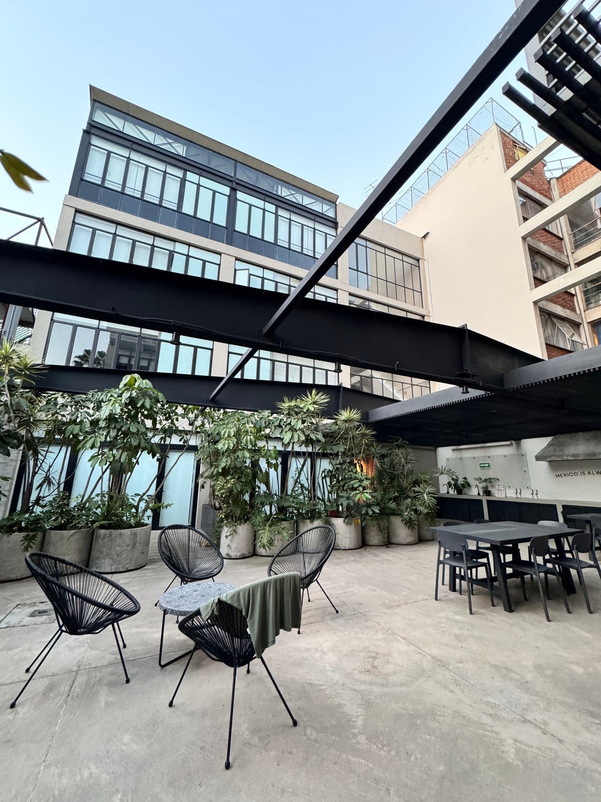 Open-air courtyard terrace with Acapulco lounge chairs and tropical plants at Outsite Mexico City Roma Sur