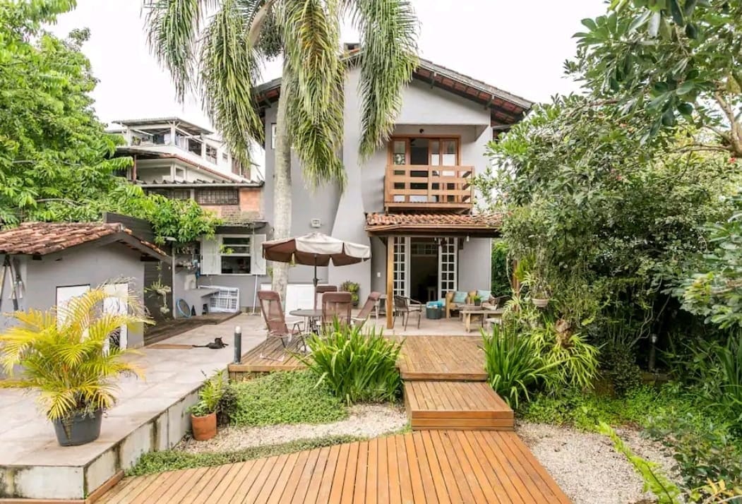 Garden and pool deck below the gabled facade of Coliving Casa Jerivá in Florianópolis