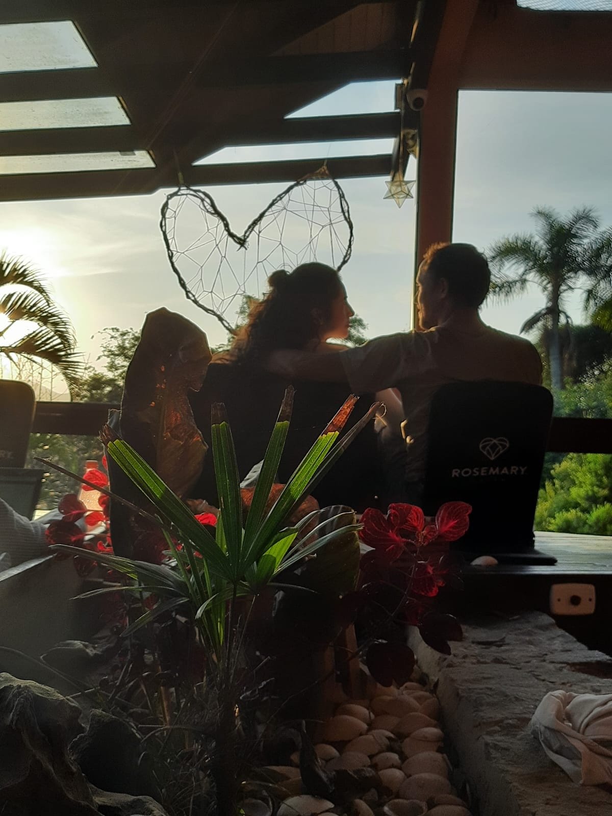 Two guests watching the sunset under the heart frame at Rosemary Dream Hostel & Coliving, Florianópolis