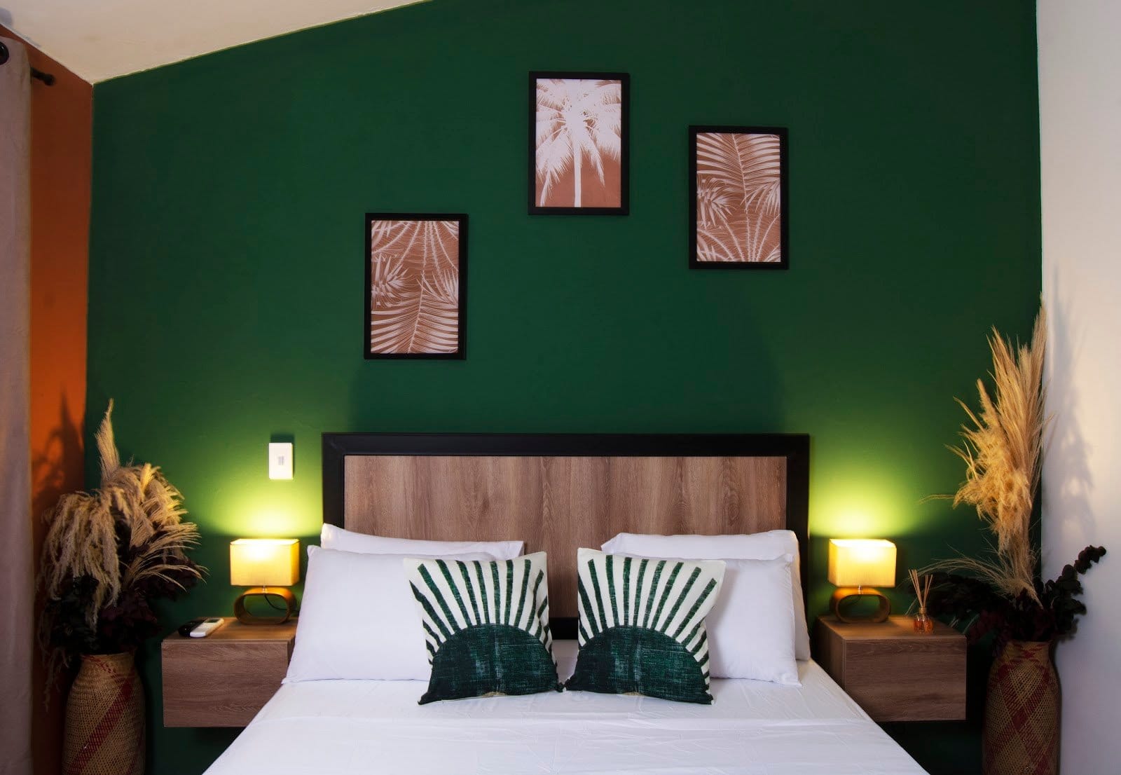 Private room at Bohemia Boutique Hostel Cali with emerald green wall, palm prints and warm lamp light