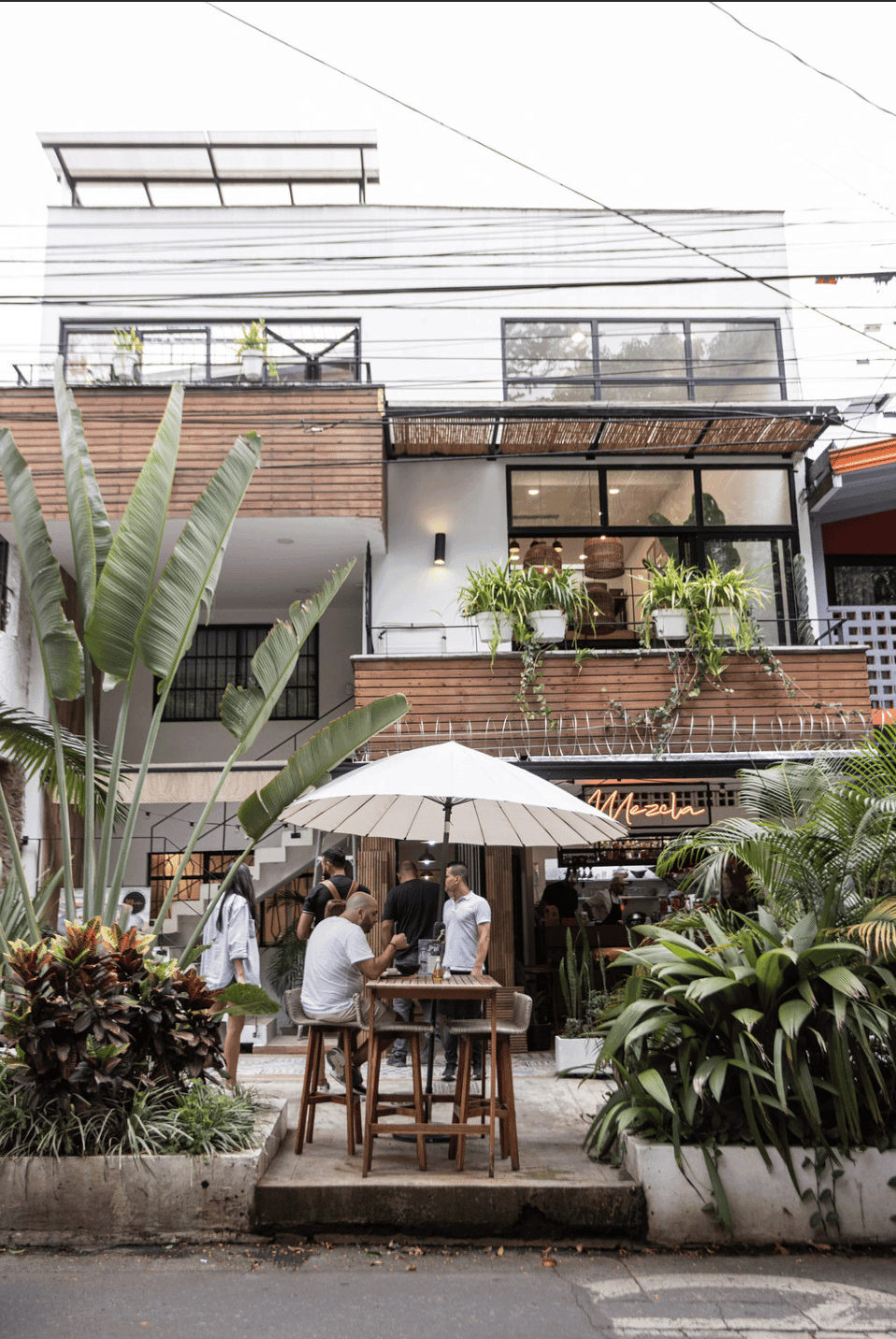 Exterior courtyard café and plant-filled facade of Outsite Medellín with guests dining