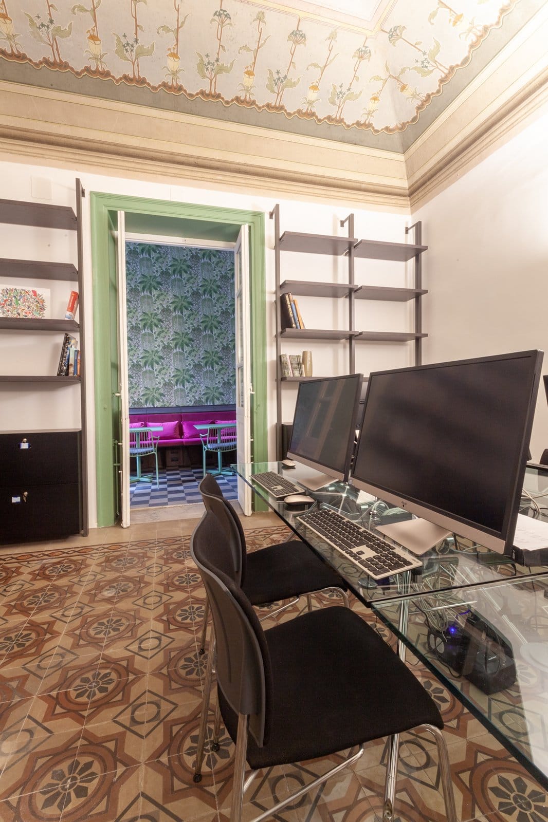 BeetCommunity coworking workstation with dual external monitors and keyboard beneath a frescoed ceiling