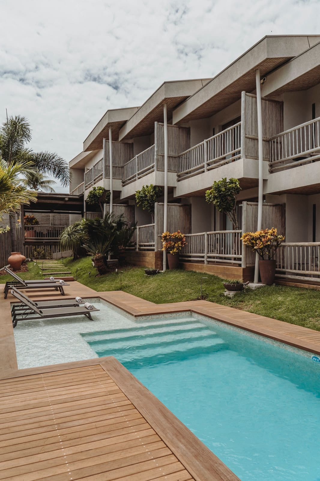 Outdoor pool and sun loungers fronting the two-story balconied guest block at Pousada Maria Bonita, Fernando de Noronha