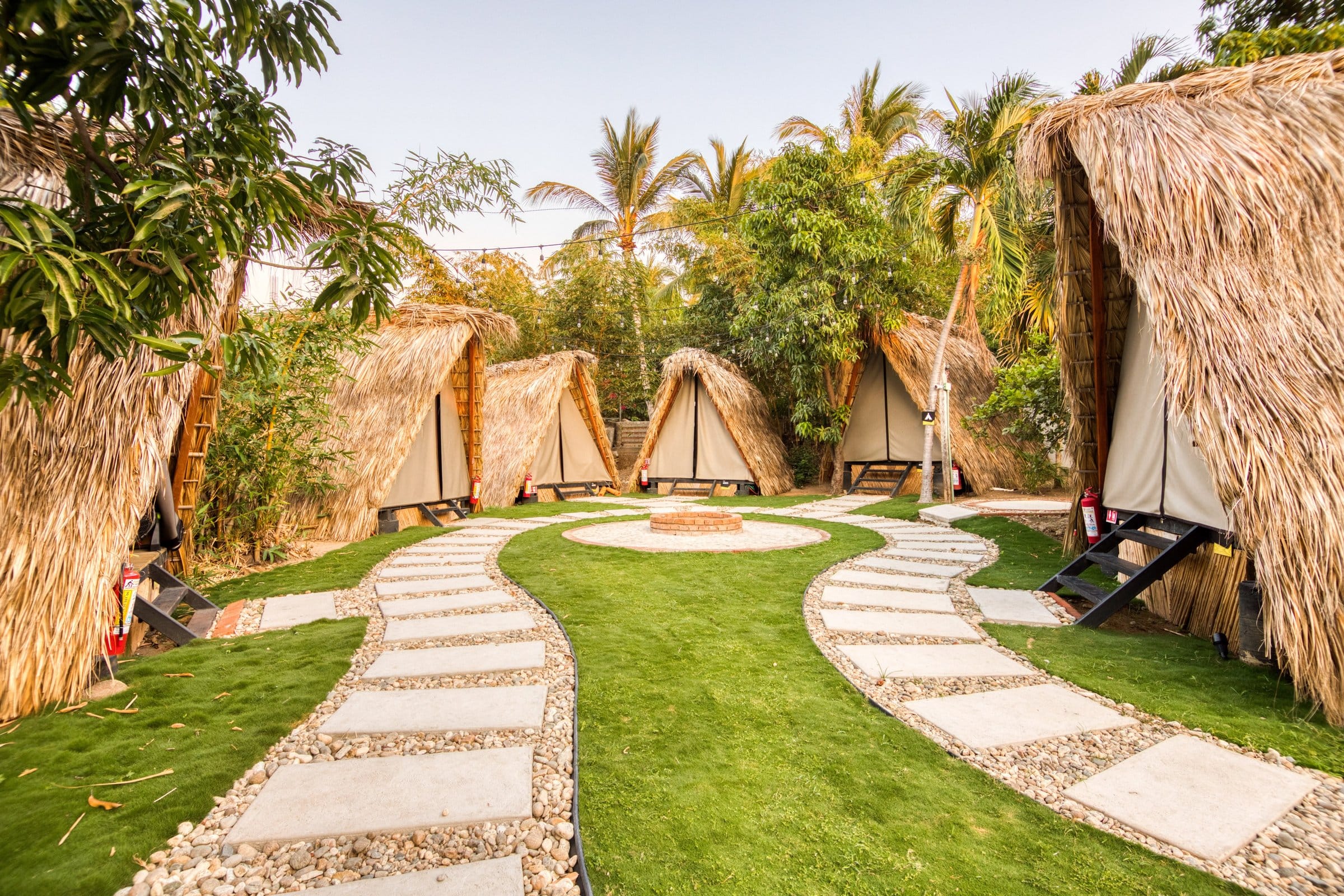 Row of A-frame glamping tents on lush grass grounds at Selina Puerto Escondido