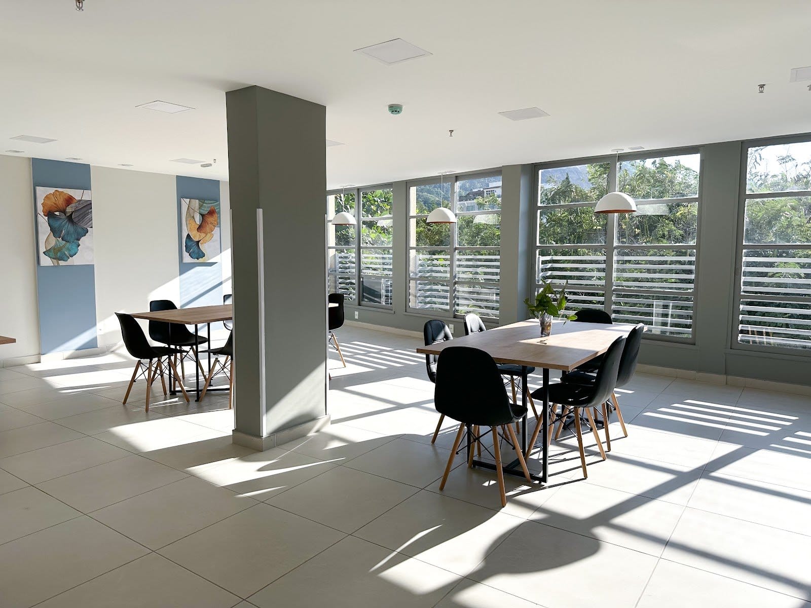 Bright communal dining area with shared tables and large windows at Vivére Coliving in Rio de Janeiro
