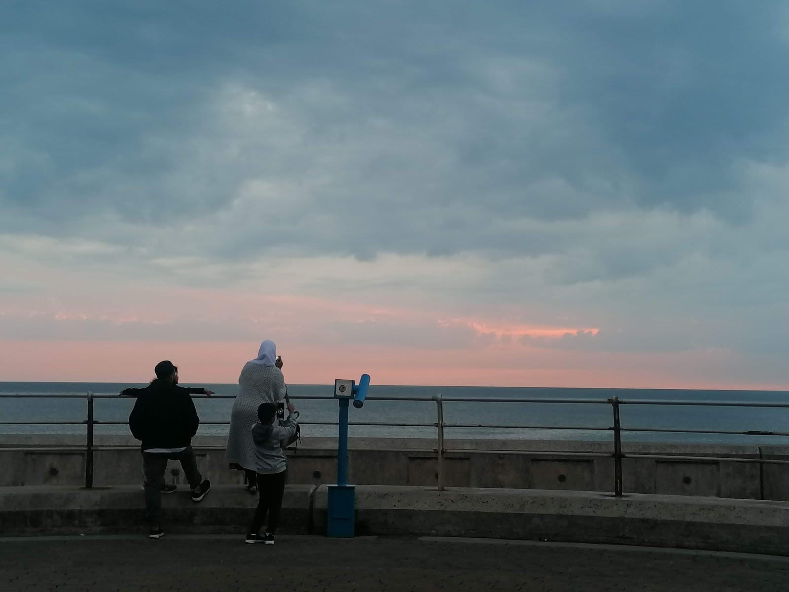 Three digital nomads leaning on the railing watching the sunset over the sea from the Blackpool promenade, just steps from Somewhere Different coliving house on the South Shore