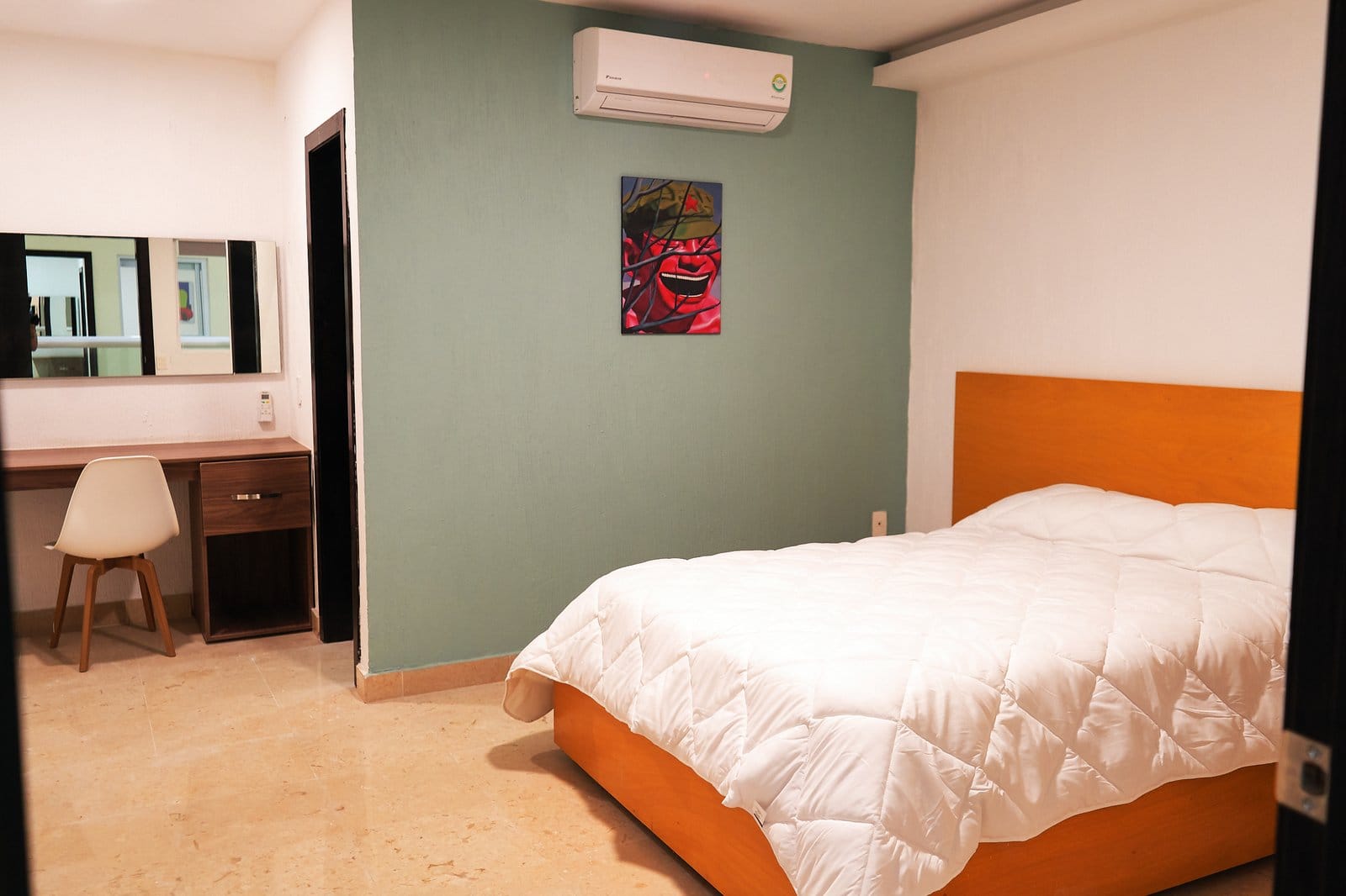 Private double room at Nora Coliving Guadalajara — orange headboard, teal accent wall, desk and colorful artwork