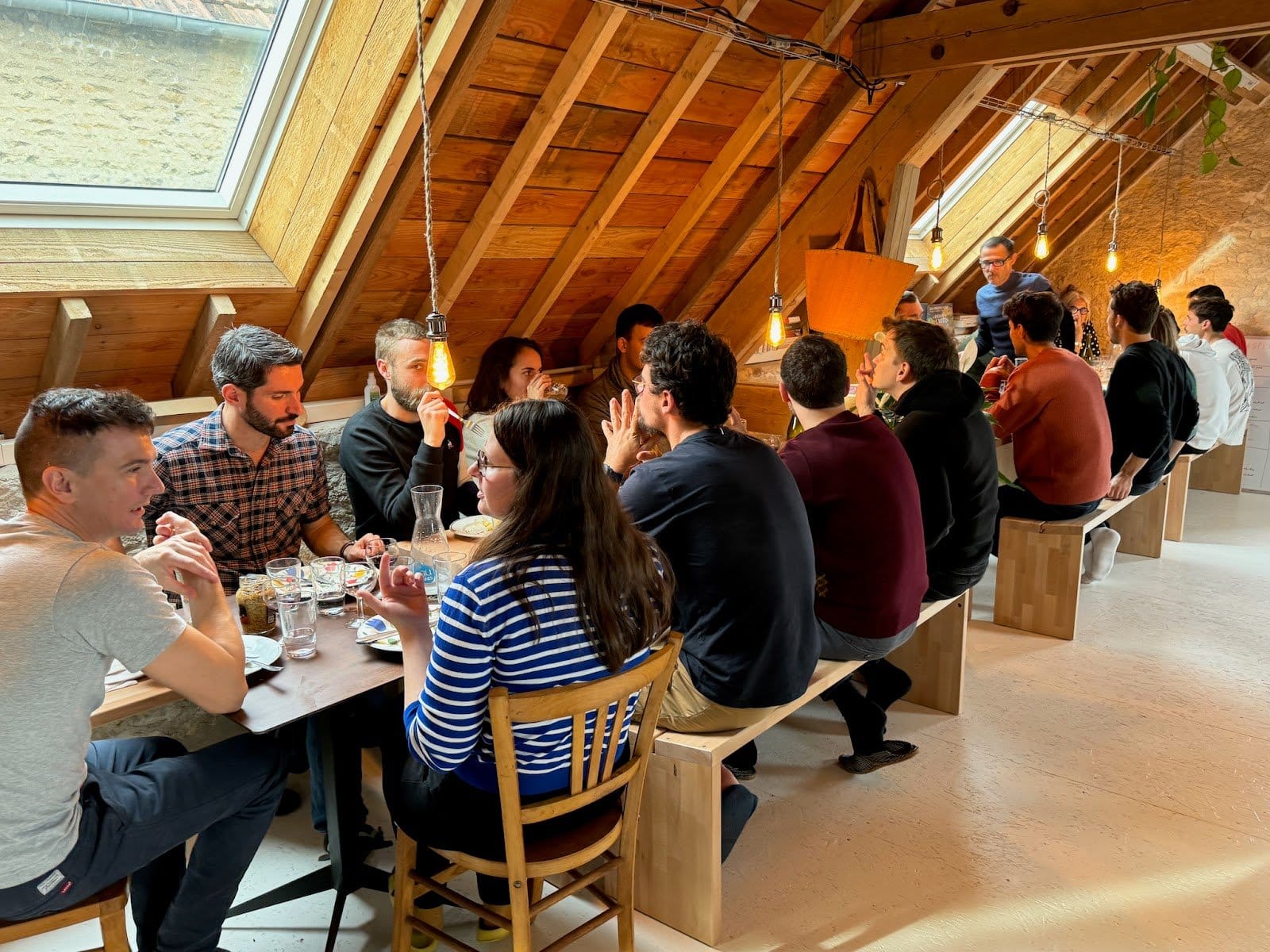 Indoor dining space with many people gathered around tables eating and conversing.