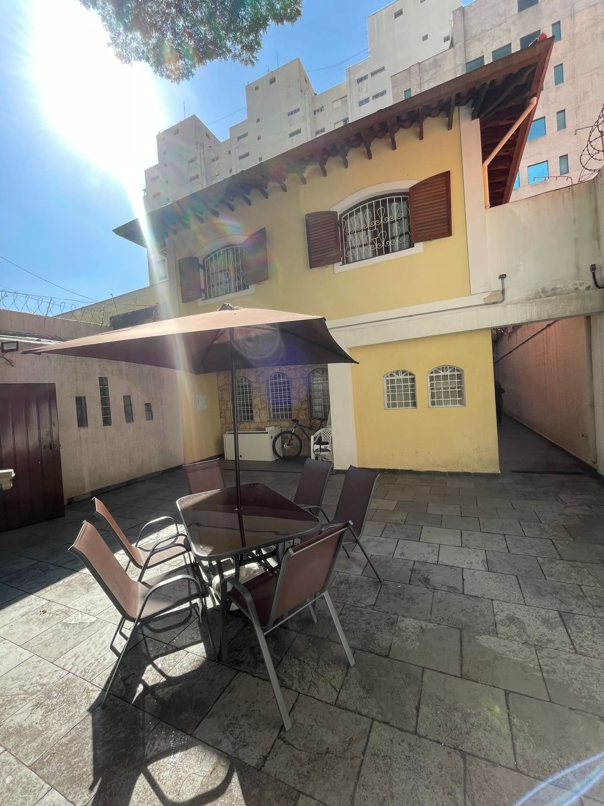 Sunlit courtyard and yellow house facade at Coliving Brooklin in São Paulo