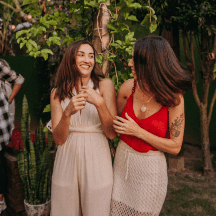 Two residents laughing together in the plant-filled garden at Coliving Muní in Florianópolis