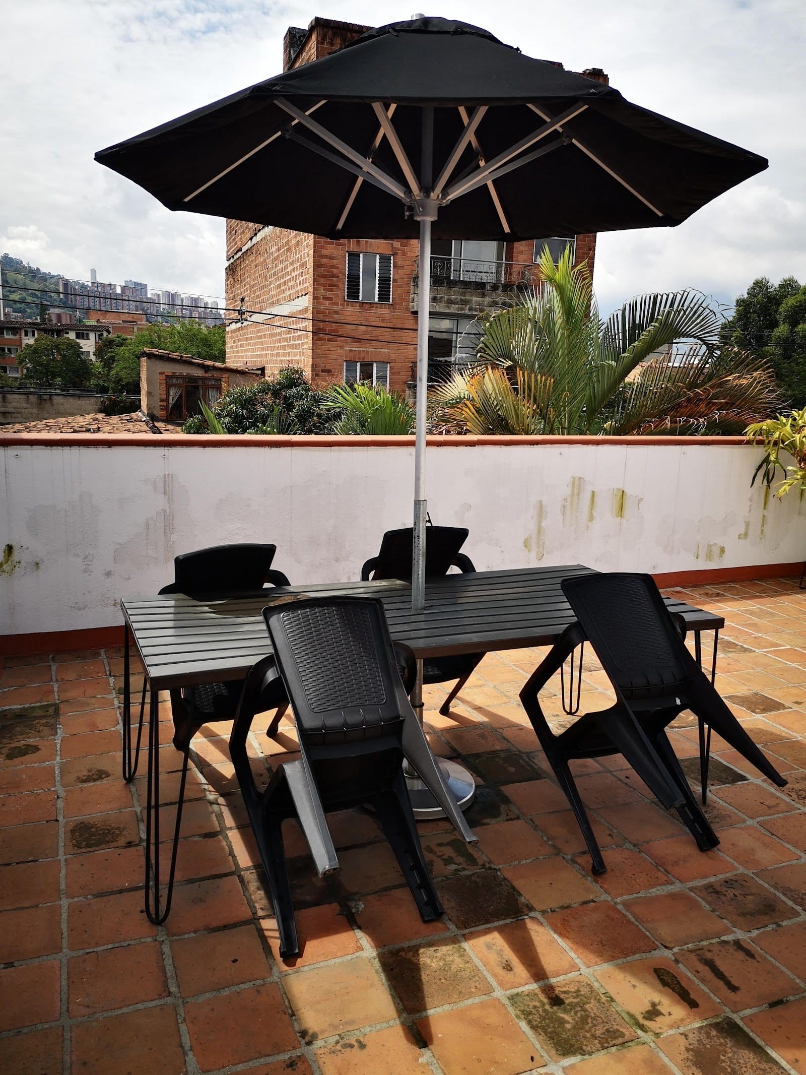 Tribu Coliving rooftop terrace with shaded dining table and views of the Medellin valley and palm trees