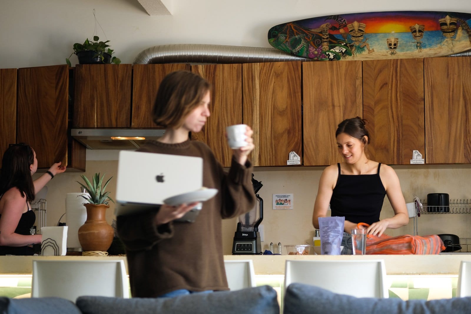 Three residents starting their morning in the Surfbreak PXM kitchen, one carrying a laptop and coffee