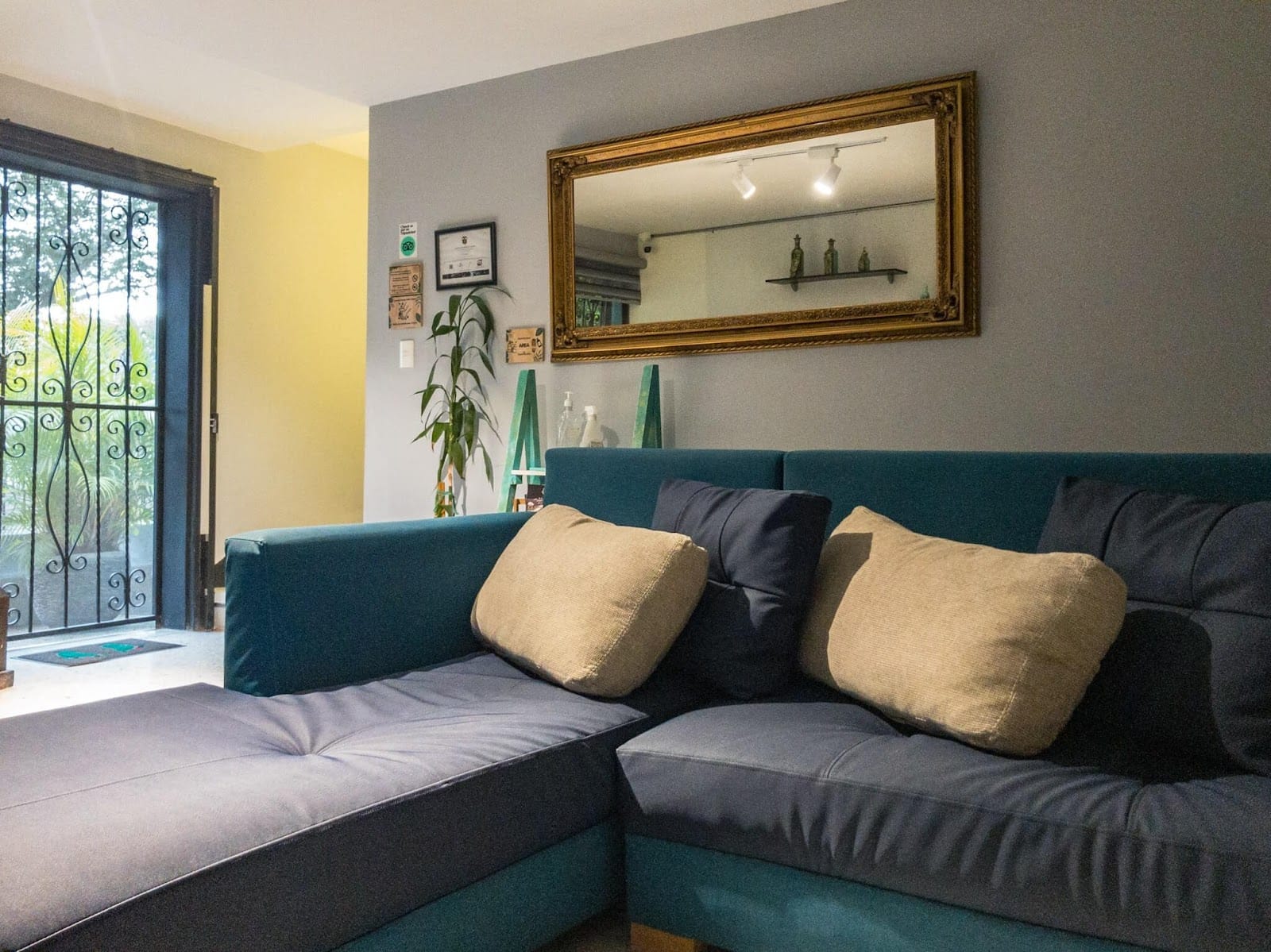 Relaxed common lounge at Pandora's House Coliving with a blue sectional sofa and gold-framed mirror