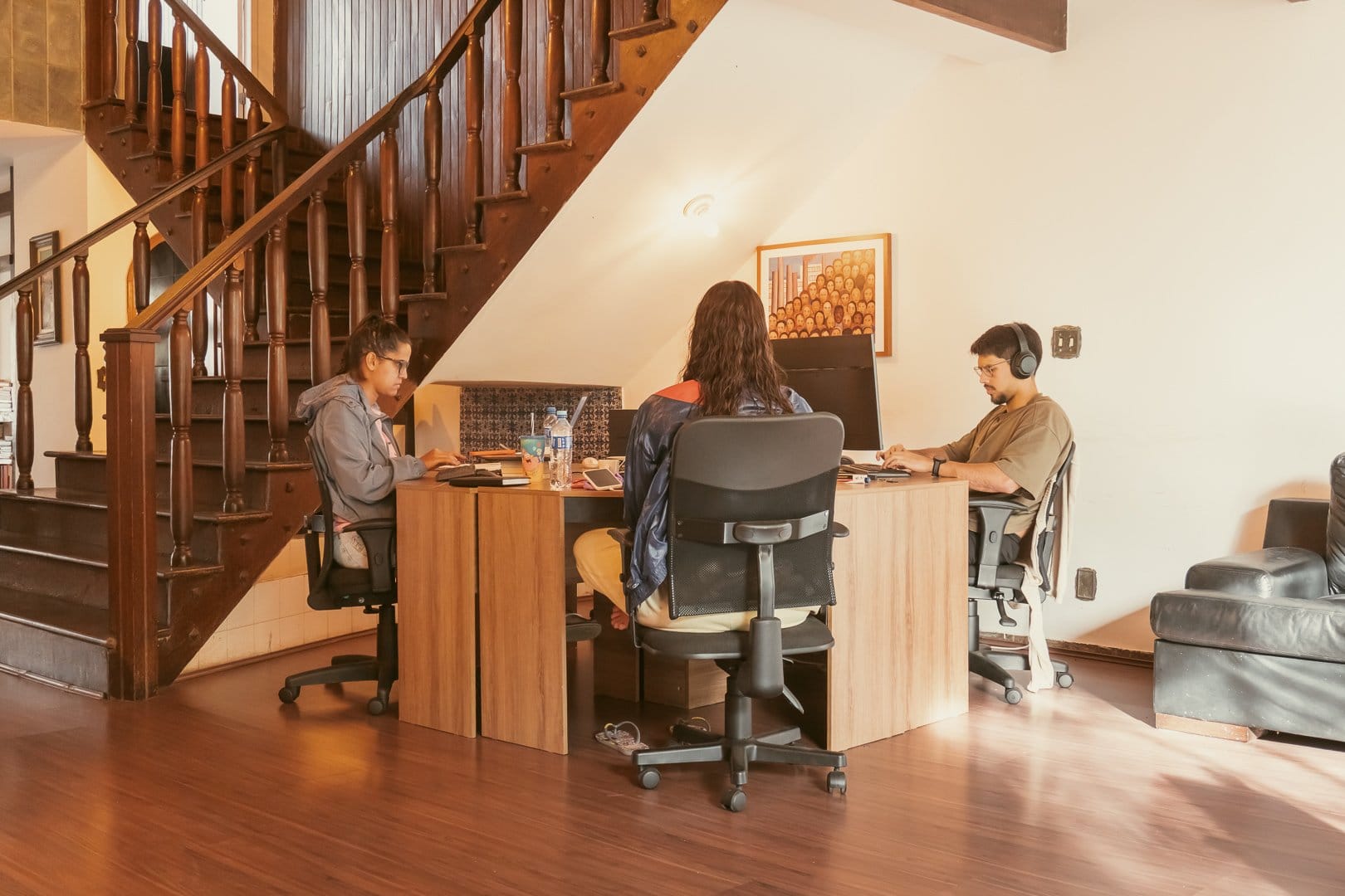 Coworking area where residents work at shared desks beneath the wooden staircase at Horizonte Coliving