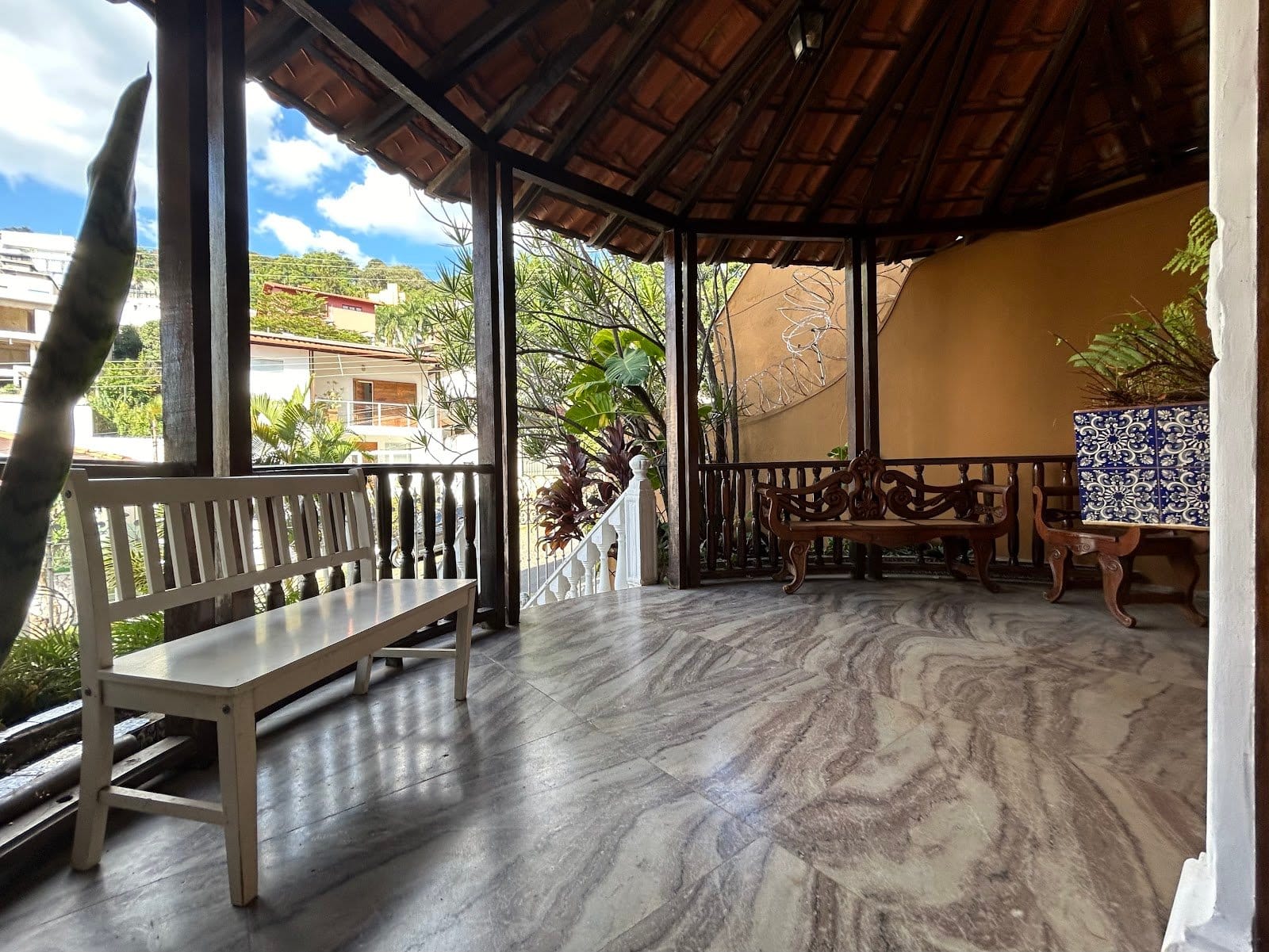 Covered terrace with marble floor, wooden ceiling and hillside city view at Horizonte Coliving in Belo Horizonte